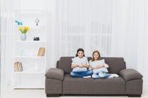 two girls are sitting on the couch