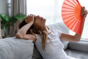 a girl is blowing hand fan to relive from heat